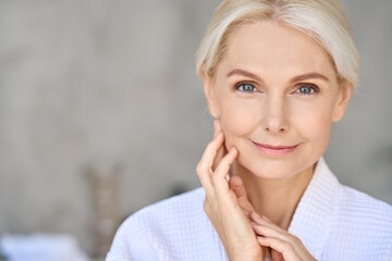 Closeup of happy smiling beautiful senior adult woman of 50s wearing bathrobe at spa hotel looking...