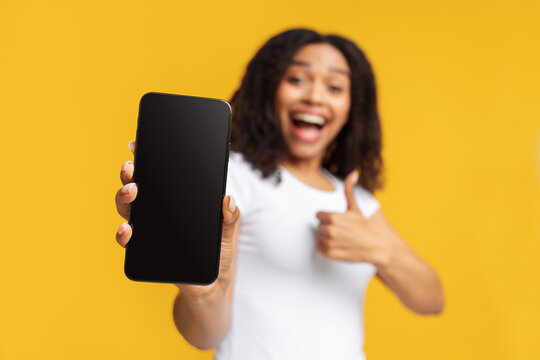 Site review and advertisement concept. Joyful african american woman showing blank screen of smartphone and thumb up