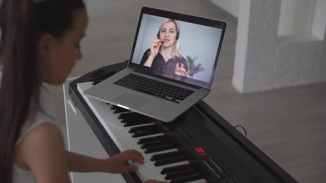 little girl play piano in class education with laptop in home online learning in covid-19 crisis quarantine