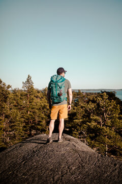 Full length of mature man standing with backpack on rock during sunny day