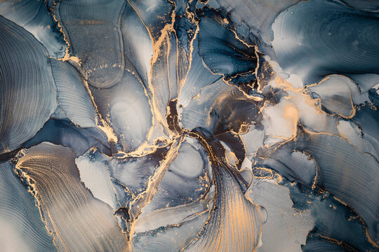 High resolution. Luxury abstract fluid art painting in alcohol ink technique, mixture of dark blue, gray and gold paints. Imitation of marble stone cut, glowing golden veins. Tender and dreamy design. © Екатерина Птушко