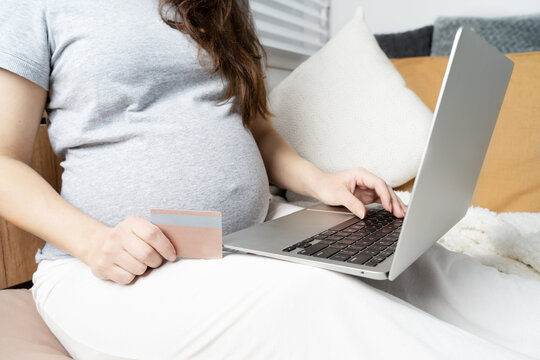 Online shopping on the Internet. Pregnant girl at the computer, pays for children's shopping with a card
