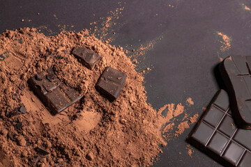 Composition of bars and pieces of different milk and dark chocolate, grated cocoa on a gray background top view close up