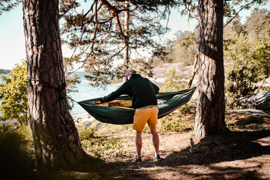 Full length of man preparing hammock in forest during sunny day