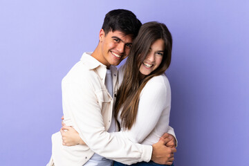 Young couple over isolated purple background hugging