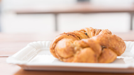 Freshly baked bagel on a white flat plate in a bakery on a table outdoors. Selective focus. Beautiful bokeh