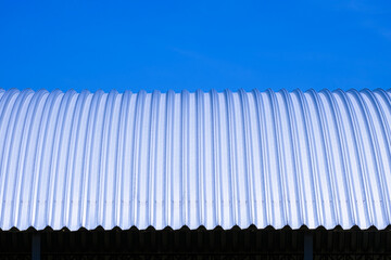 Front view of curved steel roof against blue clear sky background