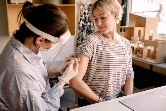 Female nurse injecting medicine to blond woman at home