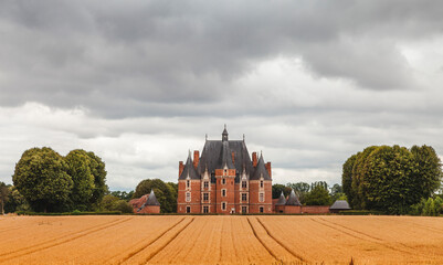 French Martainville castle surrounded in a golden field of wheat ears on a cloudy day