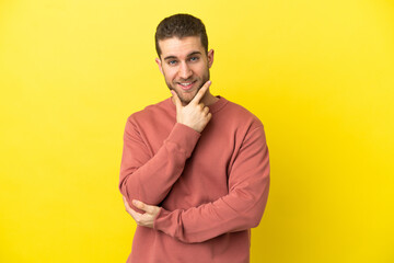 Handsome blonde man over isolated yellow background happy and smiling