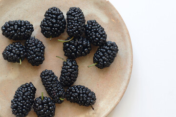 Mulberry in a pottery plate on white background