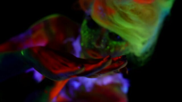 flourescent makeup and body art by glowing paints in darkness, silhouette of woman in UV lights