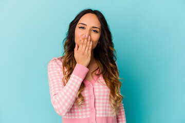 Young mexican woman isolated on blue background shocked, covering mouth with hands, anxious to discover something new.