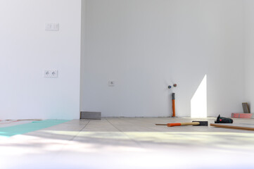 Laying laminate floor in empty white room. Finishing of houses and apartments. Redecoration in the house