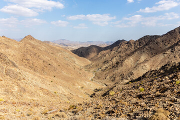 Al Hajar Mountains landscape seen from Copper Hike Summit, with rocky, dry riverbed (wadi) and barren mountain ridges, Hatta, United Arab Emirates.