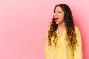 Young mexican woman isolated on pink background shouting very angry, rage concept, frustrated.