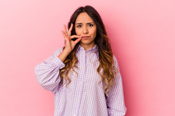 Young mexican woman isolated on pink background with fingers on lips keeping a secret.