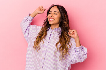 Young mexican woman isolated on pink background celebrating a special day, jumps and raise arms...