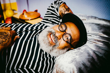 Portrait of smiling senior man winking while lying at home