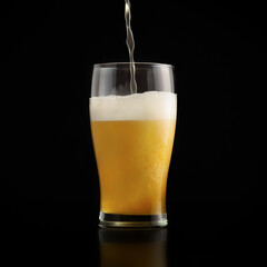 Jet of fresh light beer is poured into glass goblet on dark background with splashes and foam