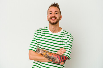 Young tattooed caucasian man isolated on white background who feels confident, crossing arms with determination.
