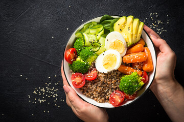 Buddha bowl. Vegan food with buckwheat, egg, avocado and fresh vegetables at black. Top view with copy space. Healthy eating, diet menu.