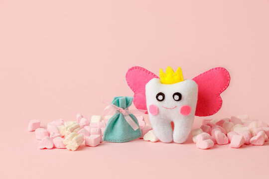 Cute toy for Tooth Fairy Day as funny smiling cartoon character of tooth fairy with crown, wings on pink background, copy space flyer, concept children milk toothless, funny toy, handmade felt diy