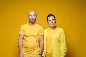 Strange man and woman in yellow robes, made stupid faces. Bright background.