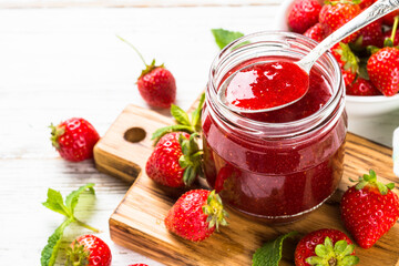 Strawberry jam in the glass jar with fresh berries. Close up.