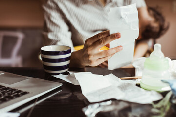 Midsection of female professional holding bill while working at home