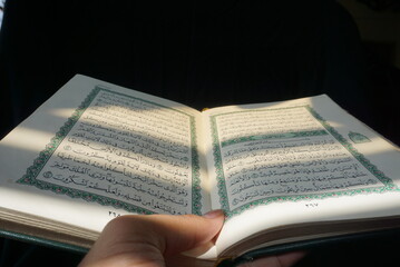 Photo of an open Islamic holy book against a black background and incoming light. suitable as a photo with the theme of religion and events of Islam or Ramadan