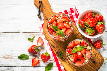 Greek yogurt with fresh strawberry and granola. Parfait in the glass jars. Top view with ingredients.