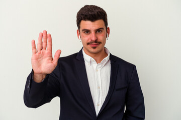 Young business caucasian man wearing wireless headphones isolated on white background smiling cheerful showing number five with fingers.