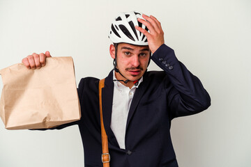 Young business caucasian man wearing bike helmet and holding take way food isolated on white background being shocked, she has remembered important meeting.