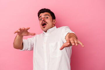 Young caucasian man isolated on pink background being shocked due to an imminent danger
