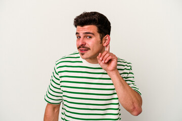 Fototapeta premium Young caucasian man isolated on white background trying to listening a gossip.