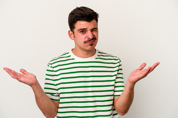 Young caucasian man isolated on white background doubting and shrugging shoulders in questioning...