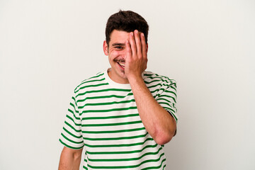Fototapeta premium Young caucasian man isolated on white background having fun covering half of face with palm.