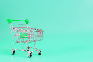 Green empty metal basket on a light green background. Close-up trading concept