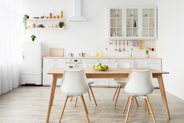 Dining room and stylish design. Wooden table and white chairs, kitchen utensils on furniture and small refrigerator