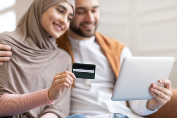 Muslim Couple Using Credit Card And Tablet At Home, Cropped