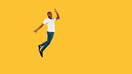 Fototapeta na wymiar Black Guy Jumping Looking Aside In Shock On Yellow Background