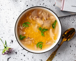 Bowl of chicken noodle soup on a light decorated background