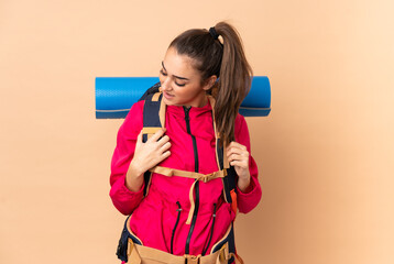 Young mountaineer girl with a big backpacker isolated on beige background