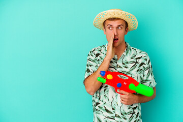 Young caucasian man wearing a summer clothes and holding water gun isolated on white background