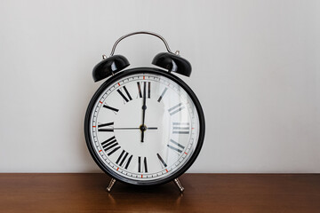 Vintage analog alarm clock on the wooden table