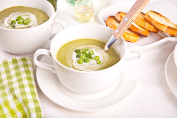 Delicious vegetable soup with potato, broccoli, green pea and spinach on the dinner table