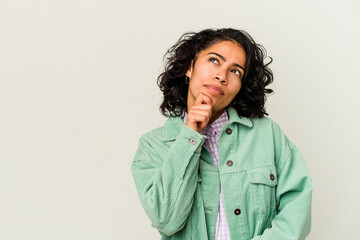 Young curly latin woman isolated on white background looking sideways with doubtful and skeptical expression.