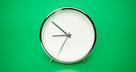 Silver Alarm clock isolated on green background, Time starts walking at 9 o'clock.