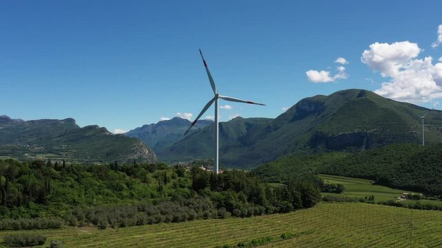 Wind turbine in Affi, Lake Garda. Wind generators in the mountains of Italy. Windmill surrounded by olive trees, vineyards, Alps. Wind turbine in Italy. Wind farm in the Alpine nature.